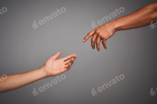 Preview: Studio shot of unidentifiable hands reaching for each other against a gray background