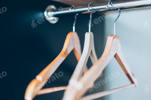 Preview: Wooden Clothes Hangers Hanging Inside of Dark Closet