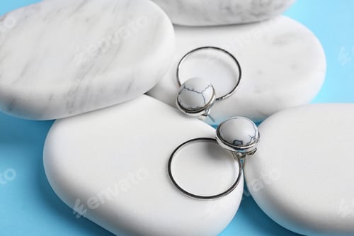 Preview: Elegant earrings and white marble on light blue background. Luxury jewelry