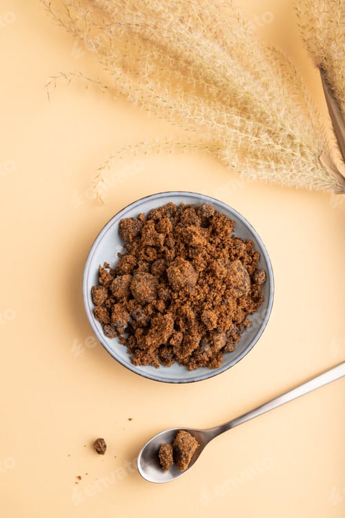 Preview: plate with unrefined cane sugar on orange pastel. top view, close up.