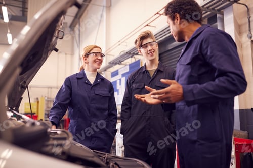 Preview: Male Tutor With Students Looking At Car Engine On Auto Mechanic Apprenticeship Course At College