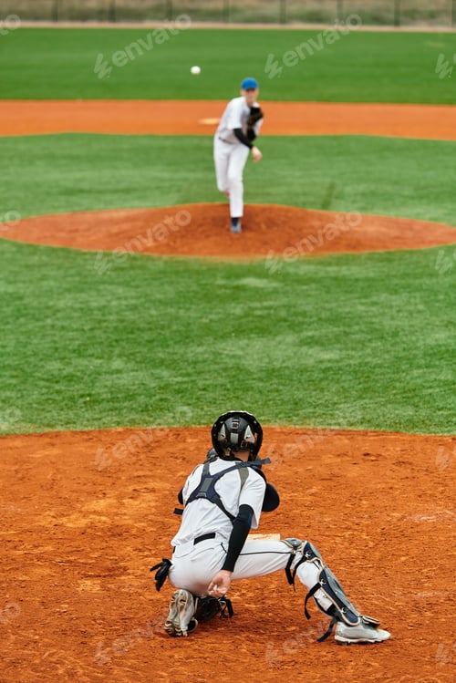 Preview: Teenage boys enjoying a friendly baseball game on an athletic field under clear skies