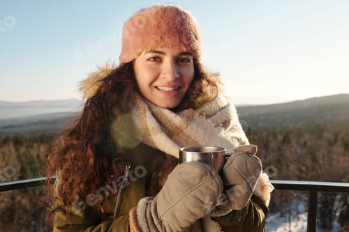 Preview: Young woman having hot tea against beautiful landscape on winter day
