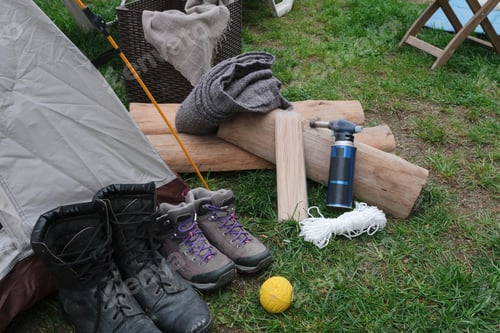 Preview: firewood, lighter and hiking accessories on green grass near tent