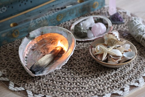 Preview: Knitted rug with bowls with shells and stones and a burning wooden stick