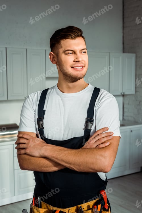 Preview: cheerful installer in overalls standing with crossed arms