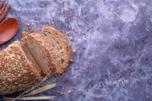 Preview: Fresh whole grain bread is beautifully displayed on a rustic table with wooden utensils