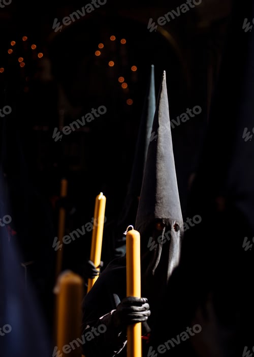 Preview: Mysterious figures in a traditional procession holding candles.