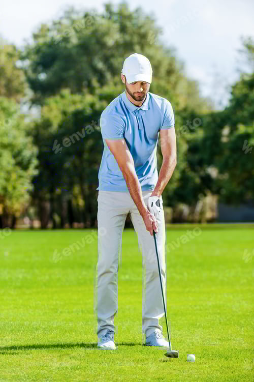 Preview: Preparing for shot. Full length of young man in sports clothing playing golf while standing on green