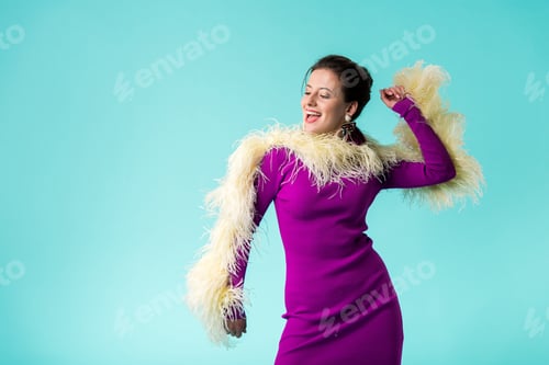 Preview: excited party girl in purple dress with feathers dancing isolated on turquoise