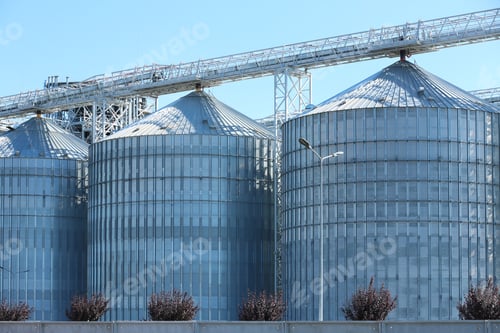 Preview: View of grain elevator against blue sky on sunny day. Cereal farming