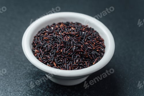Preview: Black rice in white bowl on dark background with loose grains
