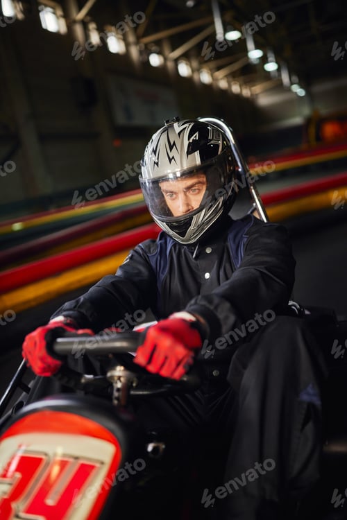 Preview: concentrated racer in helmet driving go kart car on indoor circuit, motorsport competition concept