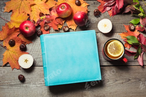 Preview: Fall concept. Blue album with space for text and cup of tea, decor of autumn leaves,