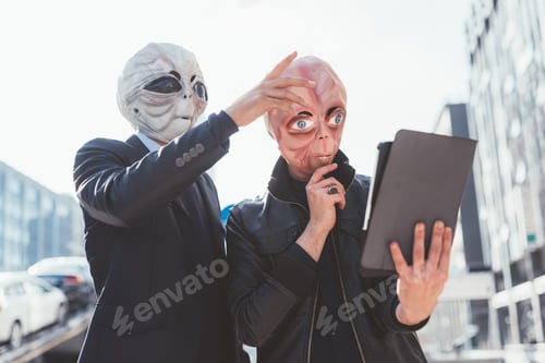 Preview: Two man wearing alien masks using tablet hand hold outdoor
