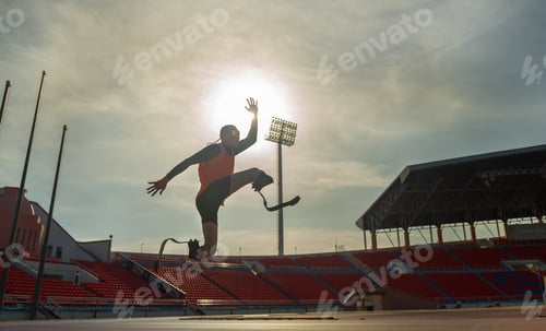 Preview: Sport man athlete prosthesis legs jump up in front of sun light in the afternoon of the stadium.