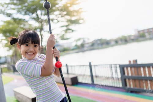Preview: Kid girl doing exercises climbing tightrope at kindergarten or elementary school.