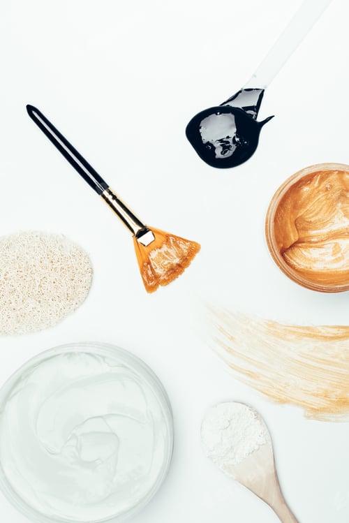 Preview: top view of sponge, spoon with clay powder, containers with clay masks, smudge and spoon with black