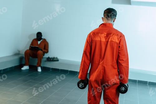 Preview: rear view of prisoner training with dumbbells in prison cell