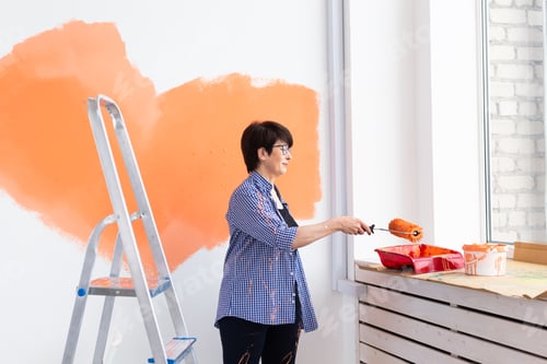 Preview: Smiling middle-aged woman painting interior wall of home. Renovation, repair and redecoration