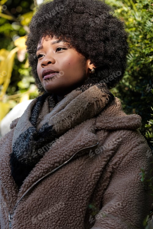 Preview: Pensive young black woman looking away outdoors.