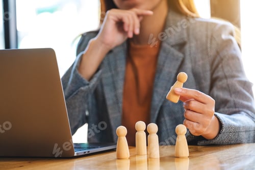 Preview: Businesswoman leader holding and choosing wooden people from a group of employees