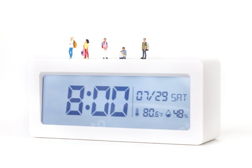 Preview: Closeup shot of little figurines of students standing on a digital alarm clock
