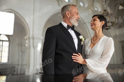 Preview: Senior Bride and Groom Looking at Each Other with Love in Church Interior