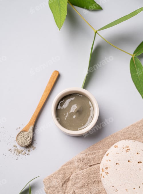 Preview: Blue clay in a bowl and spoon on a light background with leaves stone and napkin.