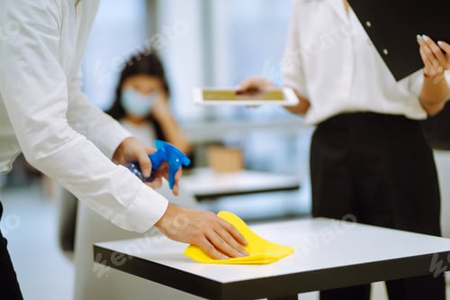 Preview: Cleaning and disinfection of the desktop. Man in protective sterile mask cleans the working desk.
