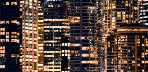 Preview: Facade windows of illuminated modern skyscraper with office building at night