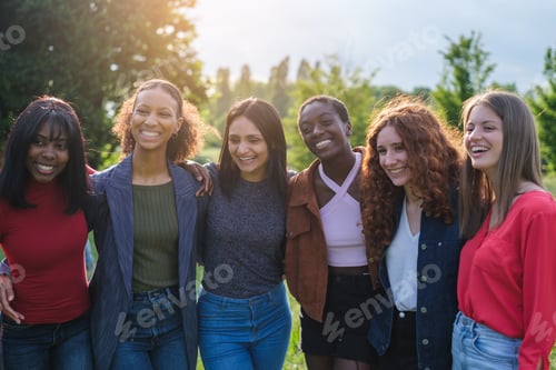 Preview: Group of young women with different cultures together outdoors at sunset in a park
