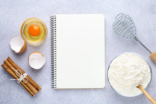 Preview: Blank recipe book, whisk and products on light table, top view. Mockup for design