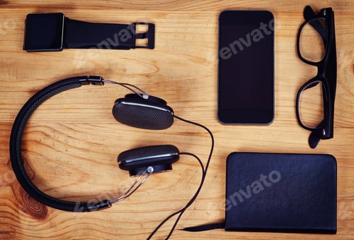 Preview: Shot of headphones, a notebook, glasses and a smartphone and smart watch on a table