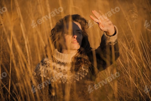 Preview: Portrait of a calm natural caucasian woman sitting in a field during sunset