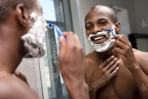Preview: handsome smiling african american man shaving and looking at mirror