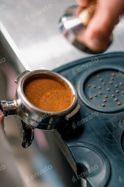 Preview: A professional barista in coffee shop prepares ground coffee by tamping fresh ground coffee beans