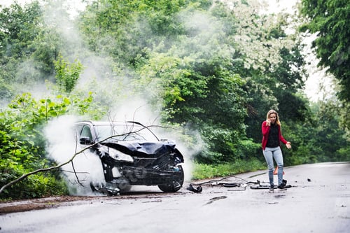 Preview: A young woman with smartphone by the damaged car after a car accident, making a phone call.