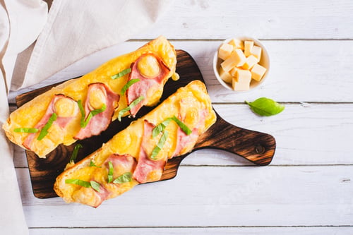 Preview: Baked baguette with bacon, cheese and herbs on a board on the table top view