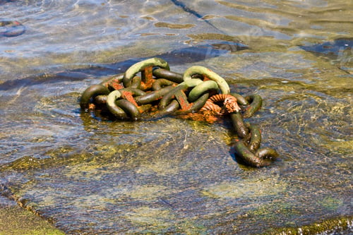 Preview: Closeup shot of an aged metal anchor chain pinned to a larger chain submerged in the ocean