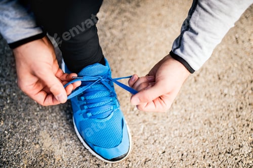 Preview: Unrecognizable young runner tying shoelaces.