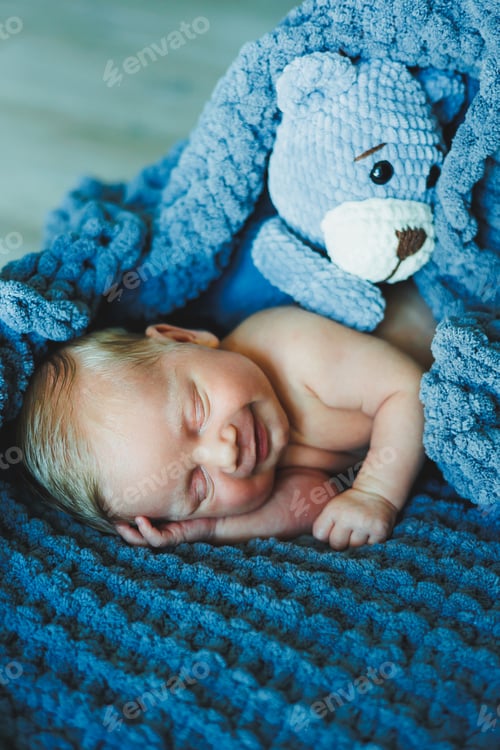 Preview: A newborn baby sleeps with a knitted teddy bear. Children's knitted toys. Baby sleep