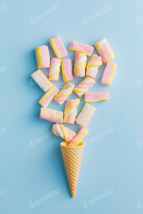 Preview: Sweet colorful marshmallows in ice cream cone on blue background. Top view.