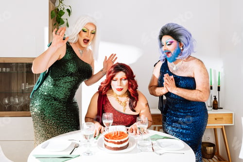 Preview: Cheerful drag queens celebrating birthday in modern apartment
