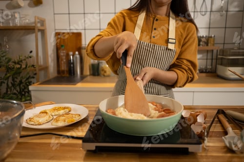 Preview: Young Asian woman preparing meal on an Induction stove in a kitchen