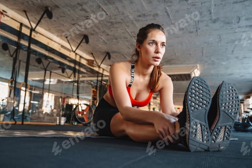 Preview: Portrait of athletic sportswoman stretching her leg while working out