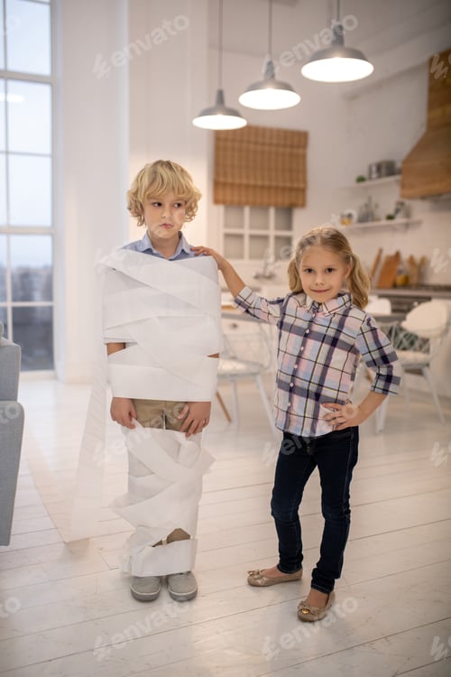 Preview: Two kids playing toilet paper mummy game at home