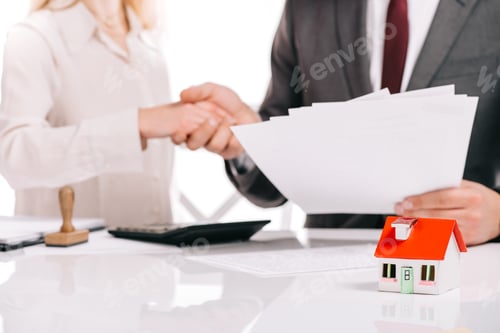 Preview: cropped view of businessman and businesswoman shaking hands isolated on white, mortgage concept