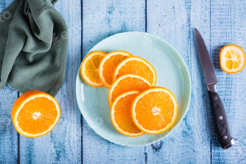 Preview: Round slices of fresh orange on a plate on the table. Vitamin antioxidant diet. Top view