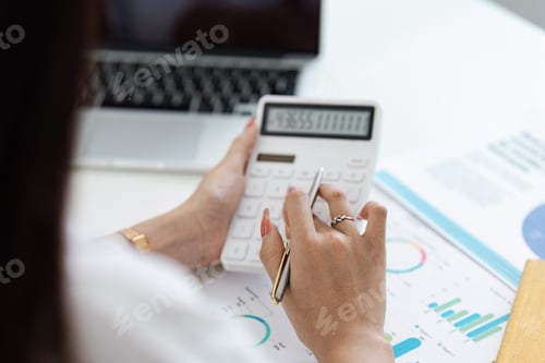 Preview: Business Professional Using Calculator for Financial Analysis with Laptop and Charts